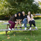 Phonathon students sitting together on a picnic table smiling
