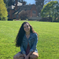 Juliana, smiling, sitting on the grass in front of the Manor House on a sunny day. Student-supplied profile photo due to COVID-19. Thank ...