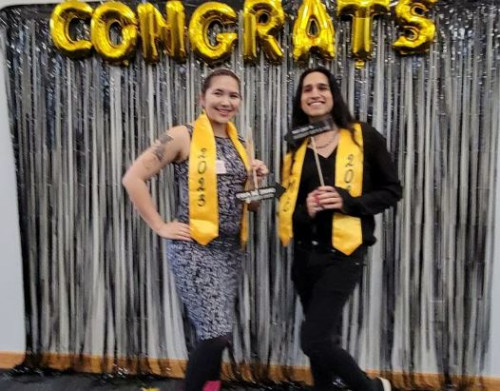 A picture of two 2023 graduates posing in front of balloons that spell out “congrats