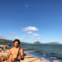 Kepa, standing on a beach, holding a guitar and looking toward the sand. Student-supplied profile photo due to COVID-19. Thank you, Kepa!