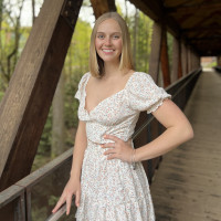 Kelsey smiling outside wearing a white dress.