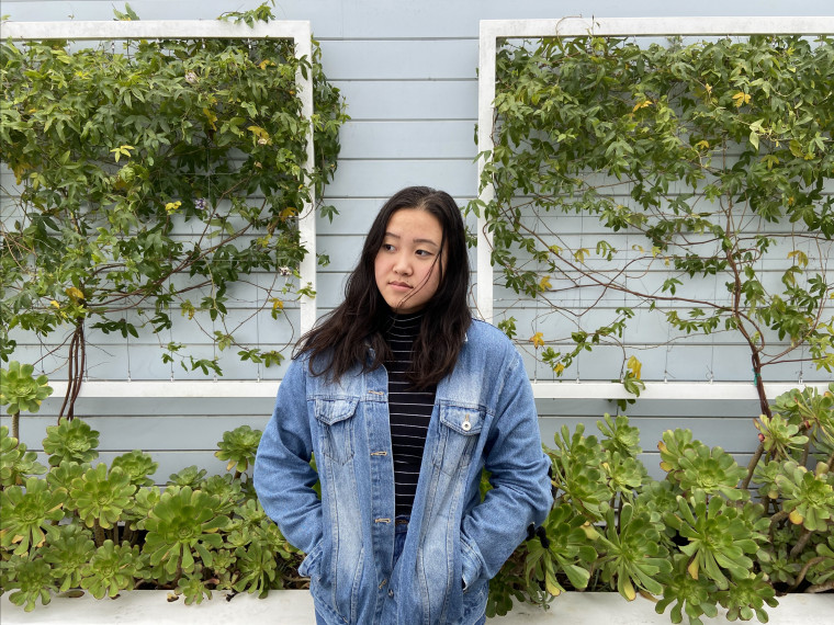 Alys, looking upward, standing in front of a vine-covered wall. Student-supplied profile photo due to COVID-19. Thank you, Alys!