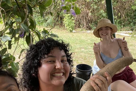 Student volunteers and leaders, Damaris, Alex, and Lily, harvest a yuca root and learn from Project YUCAE partners about its significance...