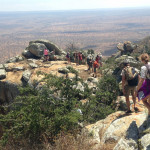 Students hiking on a rocky cliff overlooking the East Africa landscape.