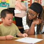 Dr. Charlene Williams sitting with a student in a classroom.