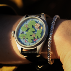 Close up of watch with a blue background, green lilypads, white flowers, and orange koi on the face.