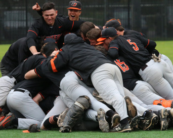 Baseball team players celebrating by jumping together in giant dog pile.